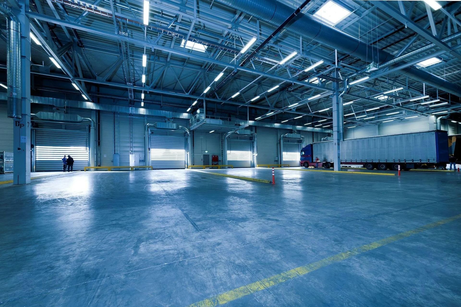 Empty industrial warehouse with polished floor and overhead lighting.